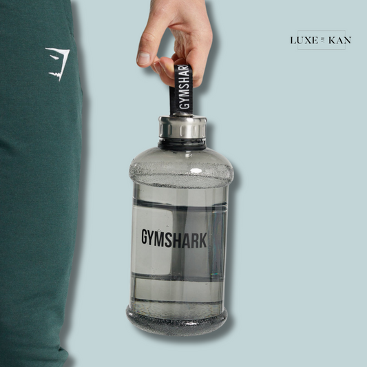 A person holds a large, transparent Gymshark water bottle with a black grip.
