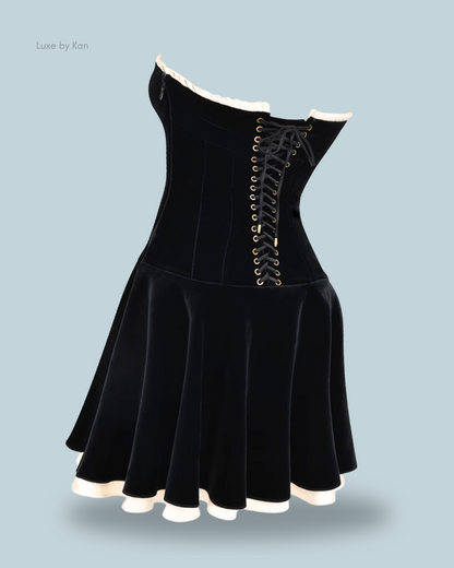 House of cb marilla black velvet strapless dress with off-shoulder design, corset lacing, and a flared skirt with a white trim at the hem.