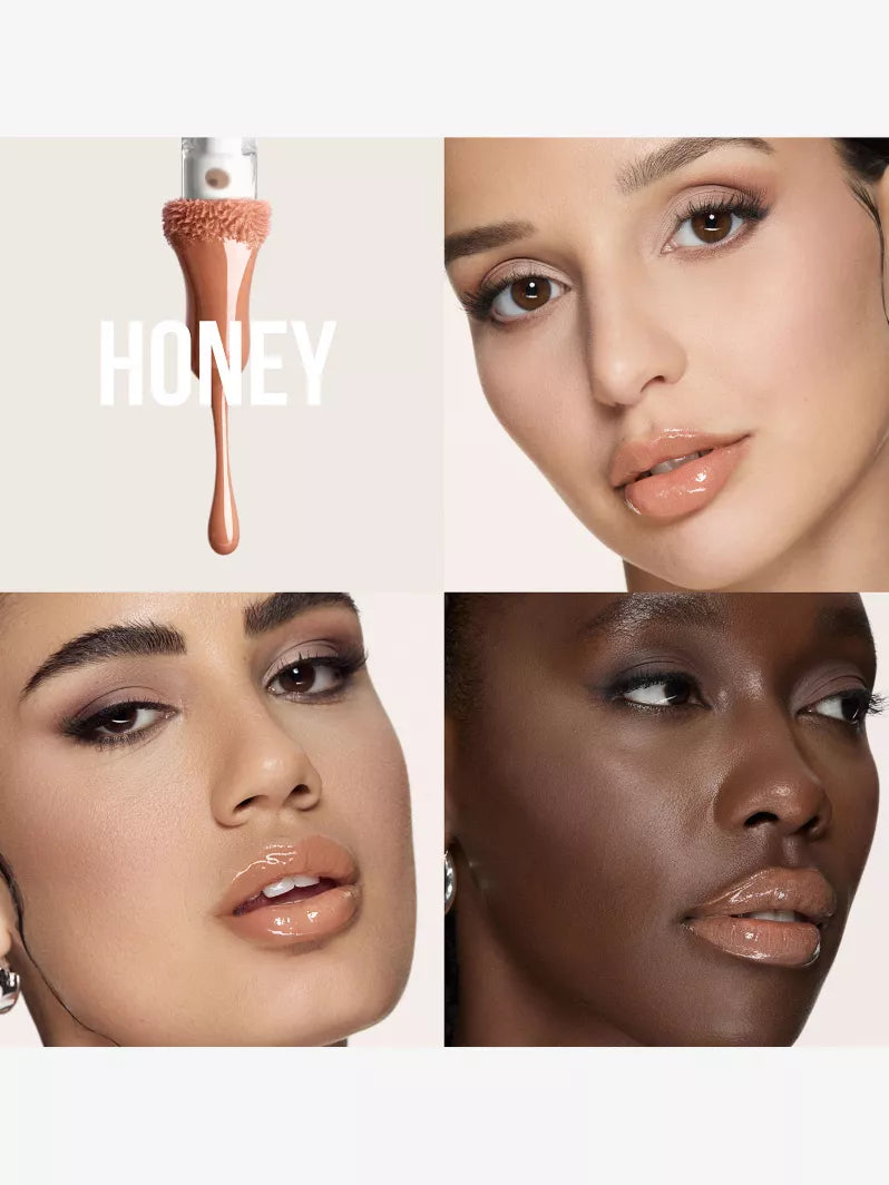 A close-up of liquid foundation labeled "HONEY" drips from an applicator against a neutral background, showcasing its creamy texture.
