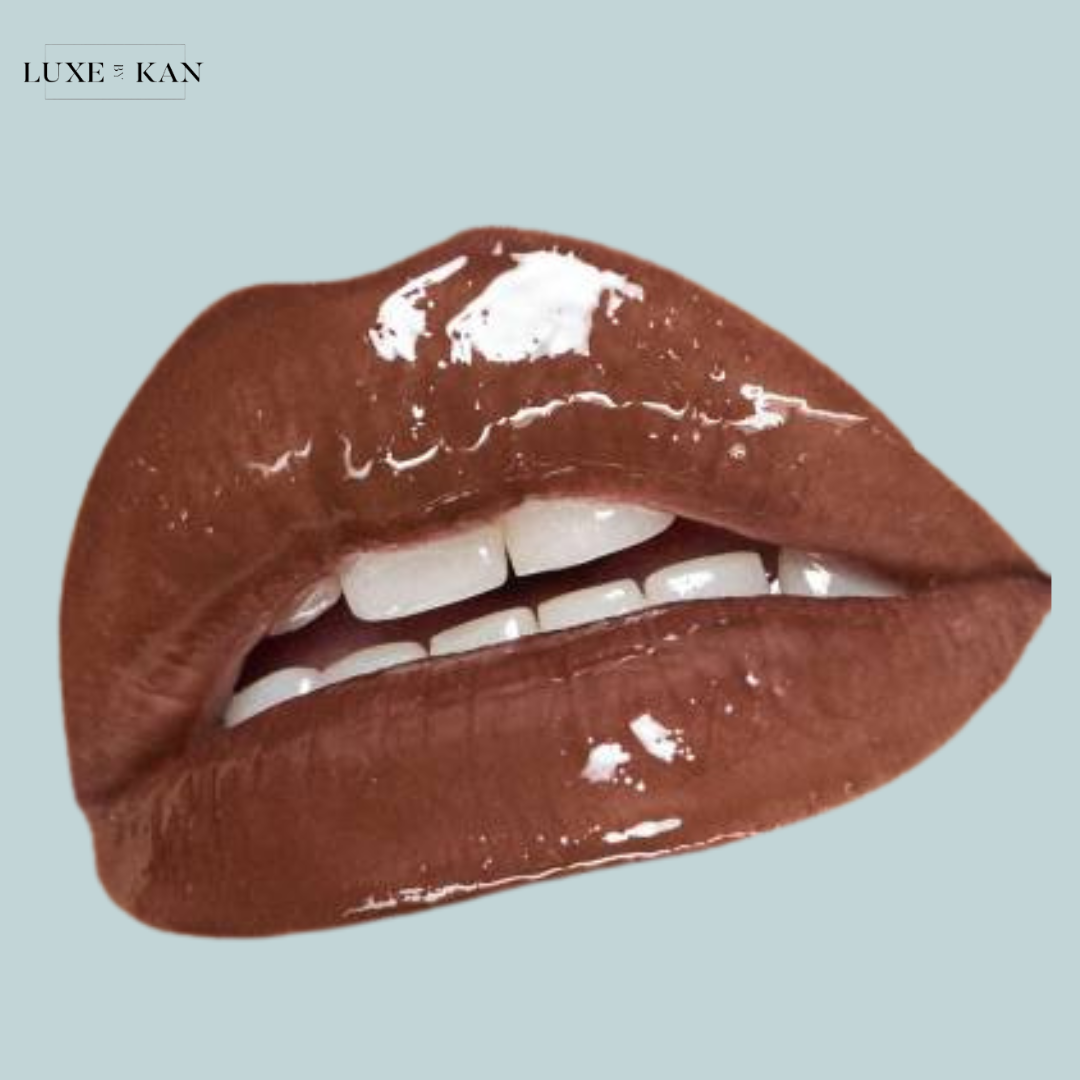 A close-up of glossy, caramel-colored lips with bright white teeth.
