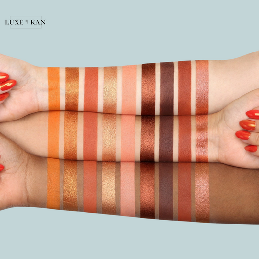 Three arms showcasing a range of warm-toned eyeshadow swatches, featuring various shades of orange, peach, and brown on different skin tones.
