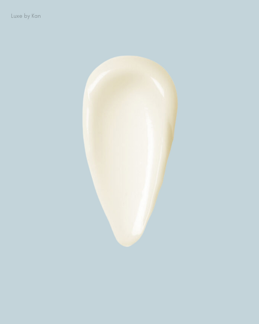 A creamy, off-white skincare product swatch on a soft blue background, showcasing its smooth texture.