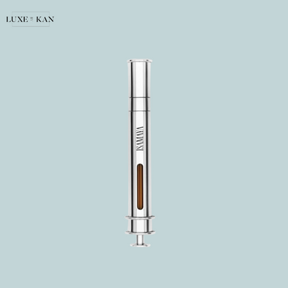 A sleek silver syringe with a transparent chamber containing a brown liquid against a soft blue background, branded "ISMAYA."