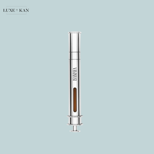 A sleek silver syringe with a transparent chamber containing a brown liquid against a soft blue background, branded "ISMAYA."