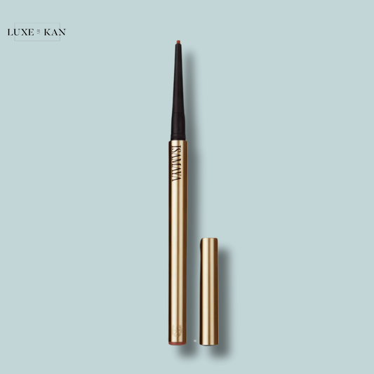 A gold isamaya beauty spur stick suede lip liner with a black tip, laying next to its removable cap.