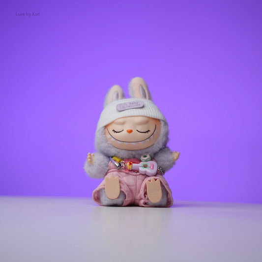 Labubu doll bunny daydream in pink quilted overalls with a bunny ear headband and mini guitar, eyes closed.