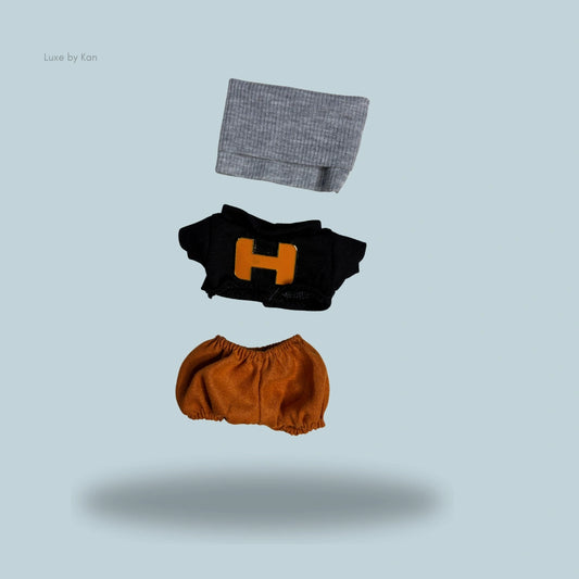 Labubu doll varsity set with grey beanie, black shirt with an orange H, and brown shorts.
