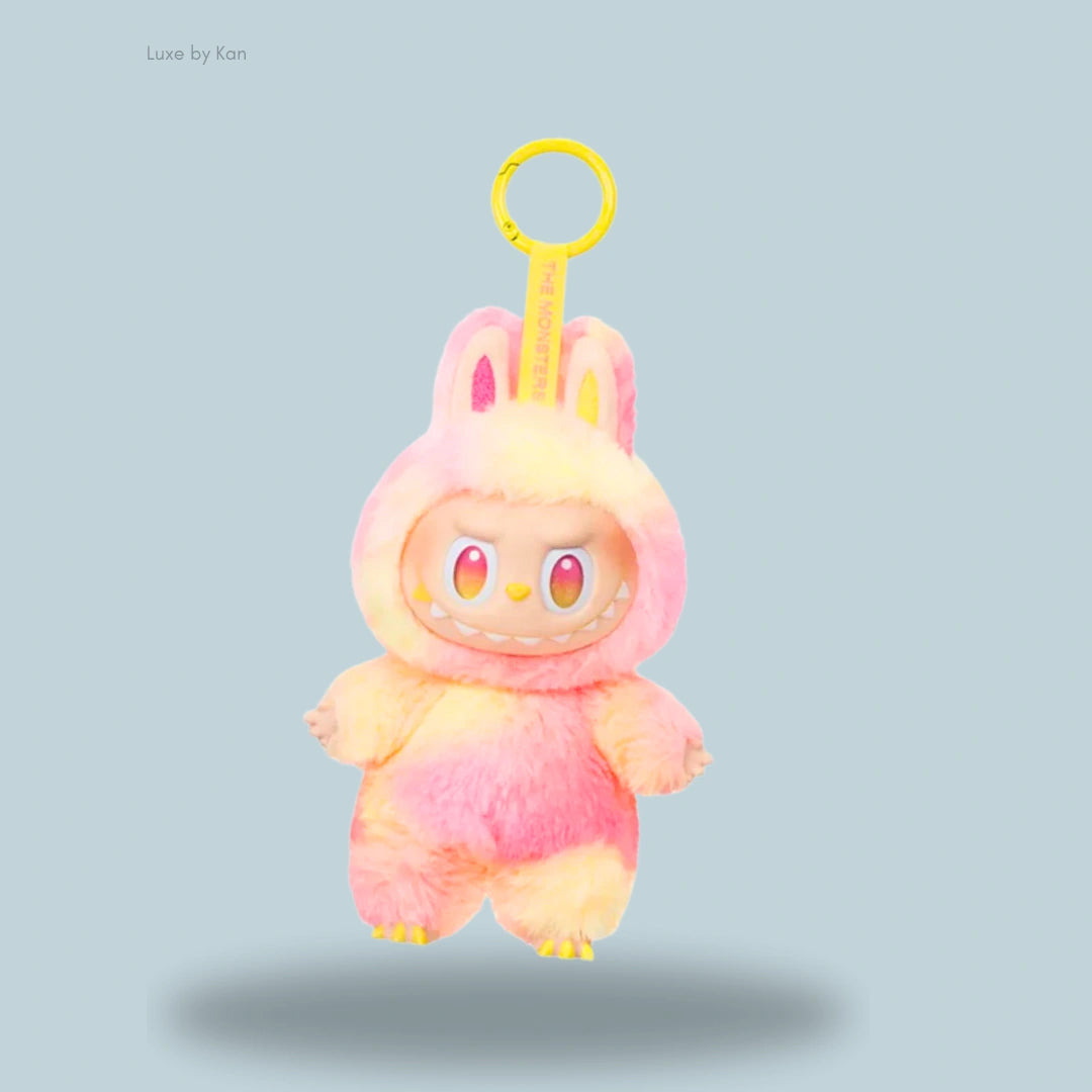 Labubu The Monsters Big into Energy Series Loyalty is a cute plush keychain featuring a pink and yellow monster with bunny ears and sharp teeth, suspended from a yellow ring.
