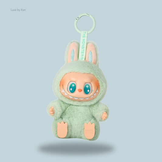 A green Labubu The Monsters Have a Seat Ququ vinyl plush bunny doll featuring a cheeky grin, big eyes, and a keychain attachment for easy display.