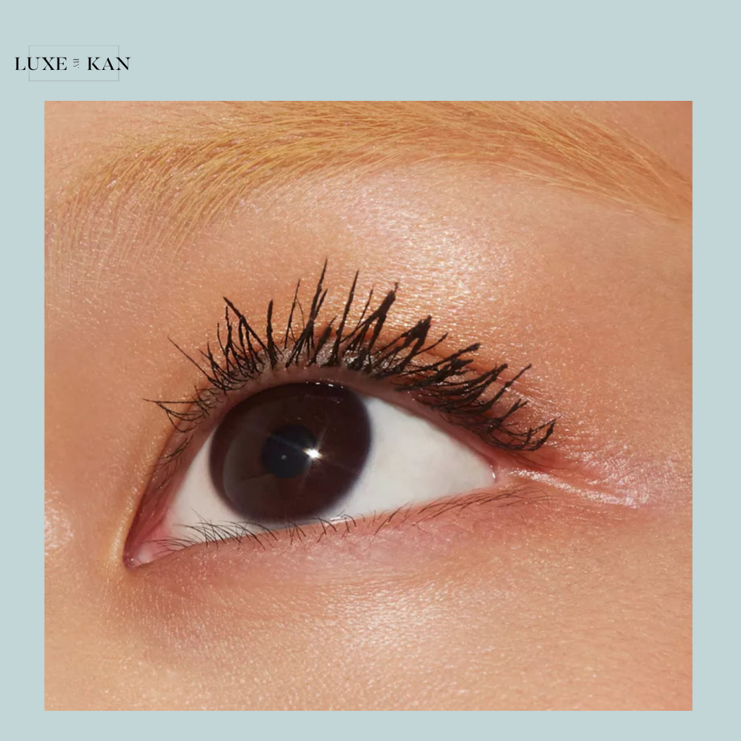 Close-up of a dark brown eye with long, defined lashes, set against smooth skin and subtle highlights. Elegant and captivating.