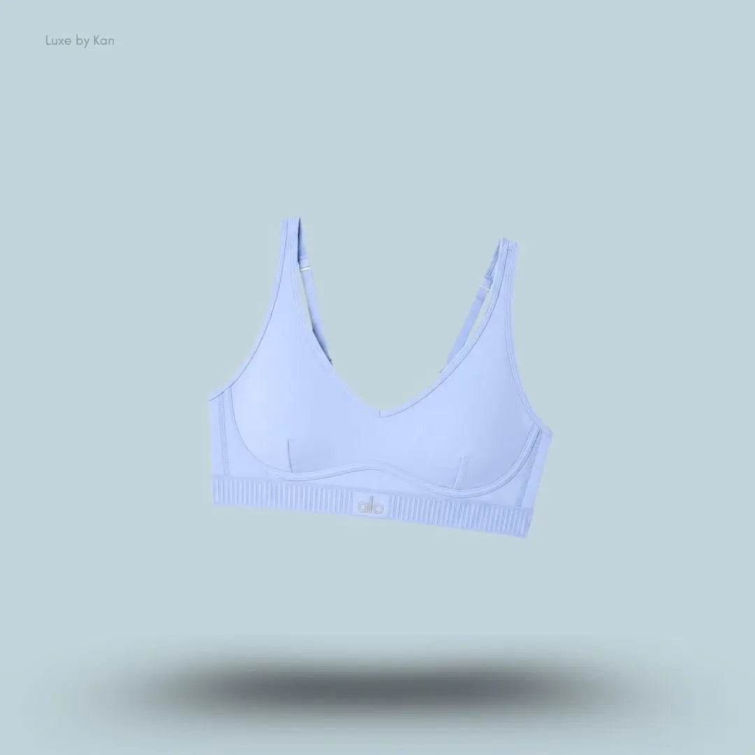 Alo Airlift Line Up Bra in Light Provence Blue, flat lay on light blue background