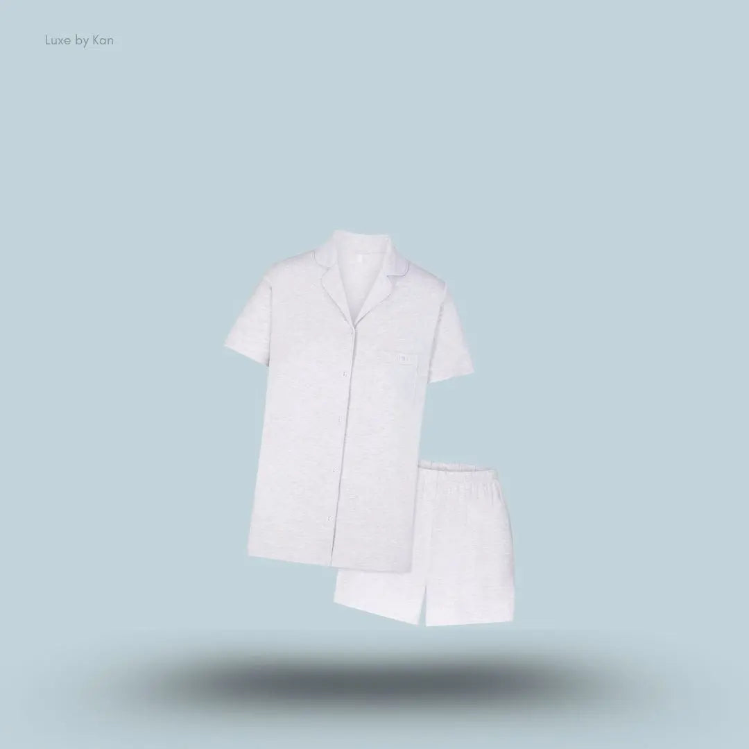 SKIMS Sleep Short Sleeve Button Up Set in Light Heather Grey, flat lay on light blue background