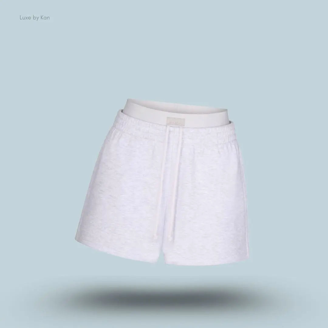 SKIMS Cotton Fleece Double Waistband Short in Light Heather Grey, flat lay on light blue background