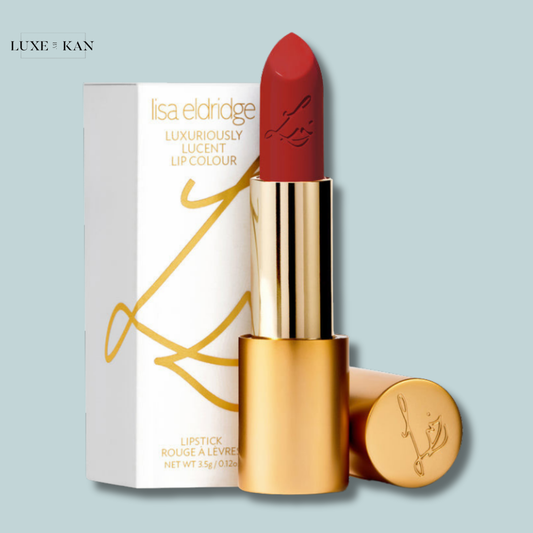 A red lipstick in a gold tube, partially exposed, next to a white box with gold accents labeled "Lisa Eldridge Luxuriously Lucent Lip Colour."