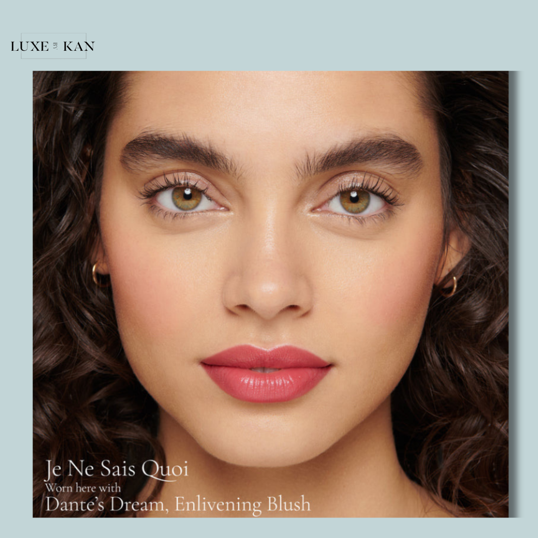 Close-up of curly hair and gold hoop earrings, featuring text promoting makeup products, "Je Ne Sais Quoi" and "Dante's Dream."