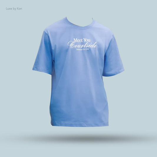 A light blue heavyweight cotton jersey Tennis Club T-shirt featuring the text “Meet You Courtside” and “Halation Est. 1998.”