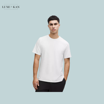 A person wearing a plain white t-shirt and black pants stands and showcasing a casual, minimalist style.