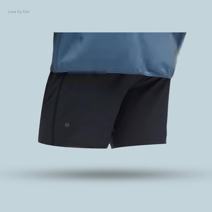 A person wearing black Pace Breaker Linerless Athletic Shorts 5" and a blue top, highlighting the shorts' sleek and sporty design.