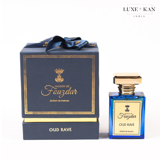 Maison de fouzdar oud rave perfume bottle next to a luxurious blue box, adorned with a golden crown and satin ribbon.
