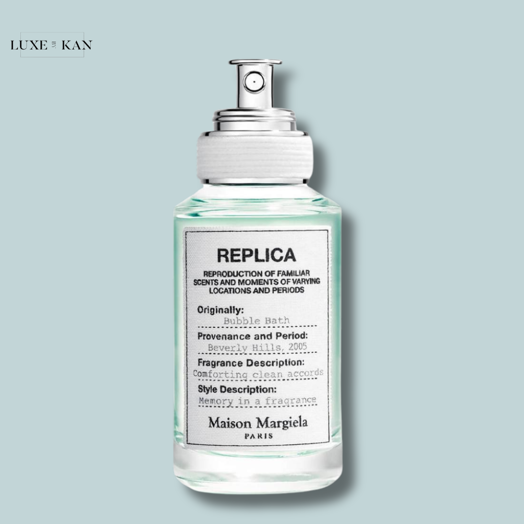 A glass perfume bottle labeled "REPLICA" by Maison Margiela, featuring details about its soothing bubble bath fragrance and origins.