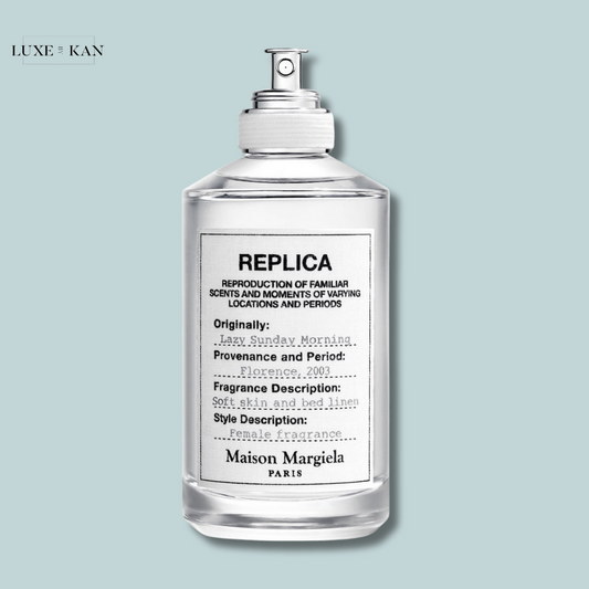 A clear perfume bottle labeled "Replica" by Maison Margiela, featuring scent details like "Lazy Sunday Morning" and "Soft skin and bed linen."