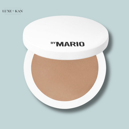A round, open compact of bronzer from 'By Mario' with a smooth, light brown shade.