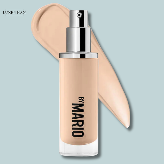 A bottle of surrealskin liquid foundation labeled "By Mario" with a pump nozzle, alongside a smooth swatch of the foundation.