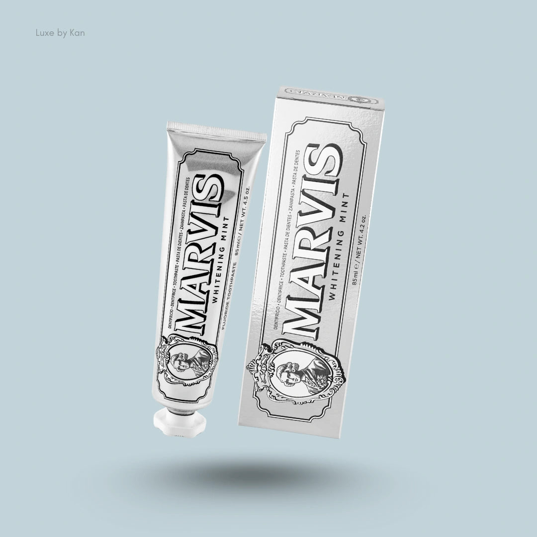 A silver tube of Marvis Whitening Mint Toothpaste next to its matching silver rectangular box on a blue background.