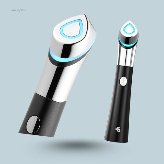 Two Medicube Age-R Booster-H devices displayed with chrome and black finish details, highlighting illuminated blue button on each device.