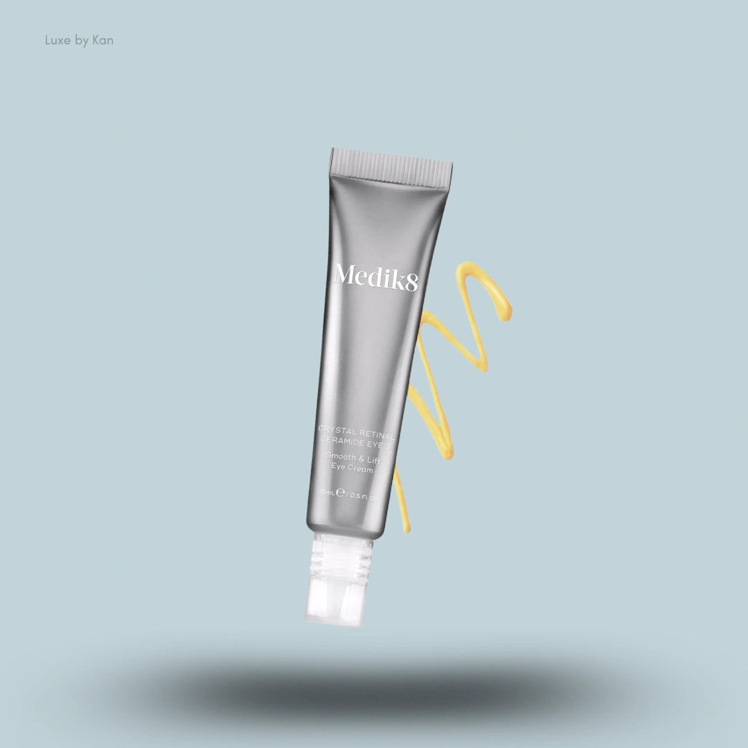Medik8 Crystal Retinal Ceramide Eye 3 silver squeeze tube with a yellow cream swirl on a light blue background.