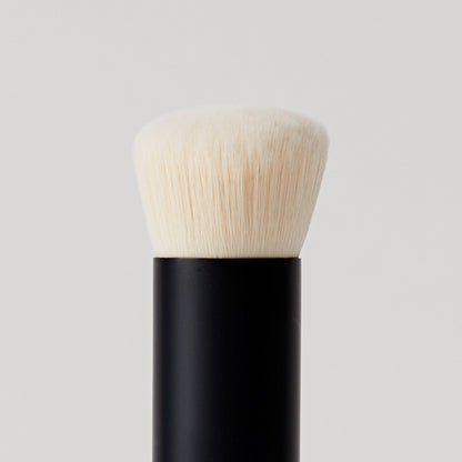 Close-up of a soft, round makeup brush with a black handle and plush.