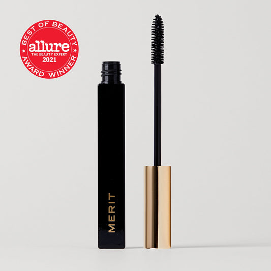 A tube of merit beauty clean lash lengthening mascara with a black wand, alongside an Allure Best of Beauty 2021 award sticker.