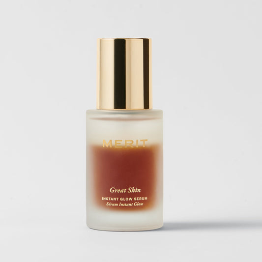 Bottle of Merit Great Skin Instant Glow Serum with a frosted glass base and shiny gold cap.