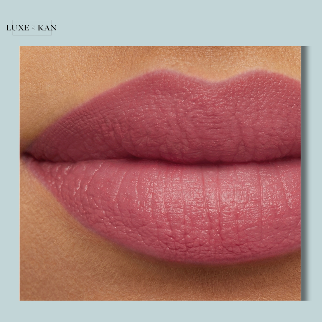 Close-up of soft, moderately matte pink lips against a light blue background, showcasing a smooth texture and natural look.