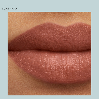 Close-up of beautifully defined, matte nude lips with a smooth texture, showcasing a soft, earthy color. Branding: Luxe & Kan.