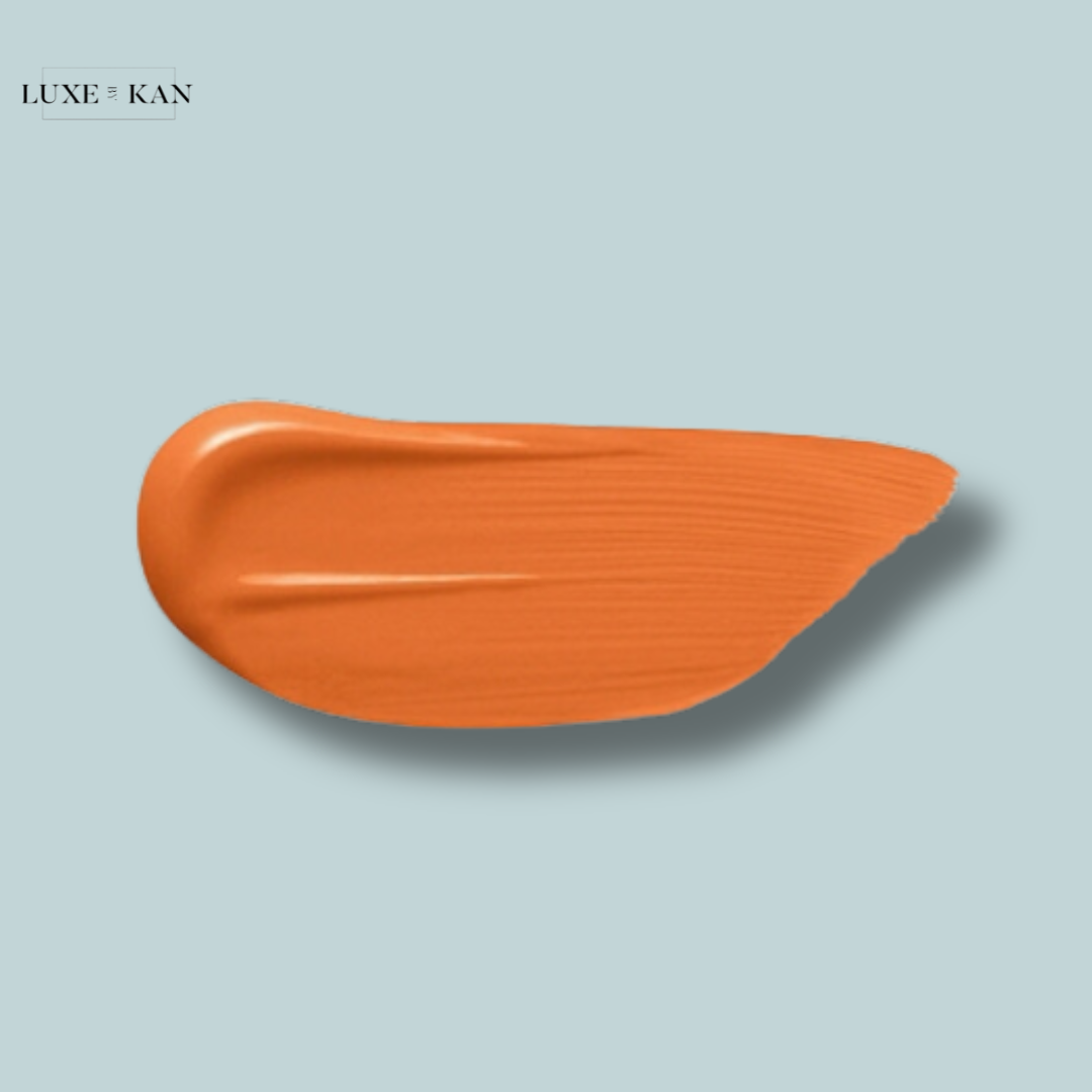 Orange makeup swatch against a soft blue background, showcasing a glossy finish and smooth texture.
