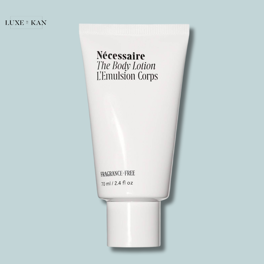 A white tube of Nécessaire The Body Lotion travel size, 70 ml, labeled "fragrance-free," set against a pale blue background.