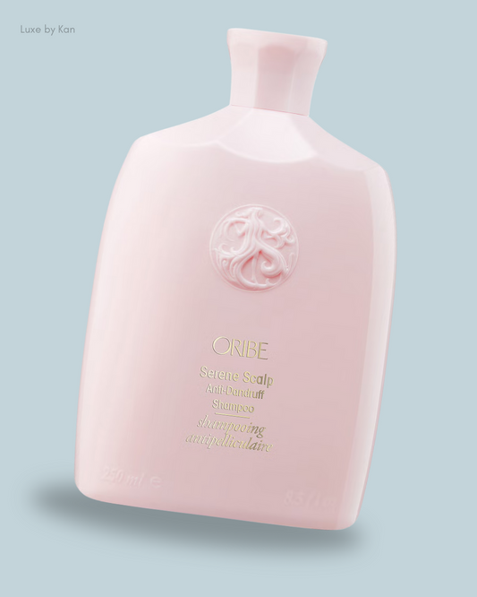 A light pink bottle of Oribe Serene Scalp Anti-Dandruff Balancing Shampoo, featuring an ornate logo and elegant design.
