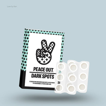 Product packaging for "Peace Out Dark Spots," featuring a peace sign graphic above the product name and twelve dissolving microneedling dots per pouch with niacinamide and tranexamic acid.