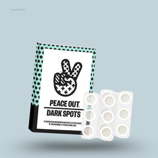 Product packaging for "Peace Out Dark Spots," featuring a peace sign graphic above the product name and twelve dissolving microneedling dots per pouch with niacinamide and tranexamic acid.