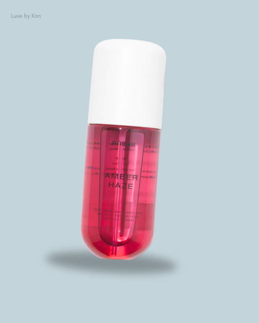 A floating pink bottle of "Amber Haze" hair and body fragrance mist with a white cap.