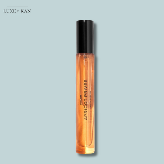 A transparent glass perfume bottle labeled "APRICOAT PRIVÉE" with a sleek black cap.