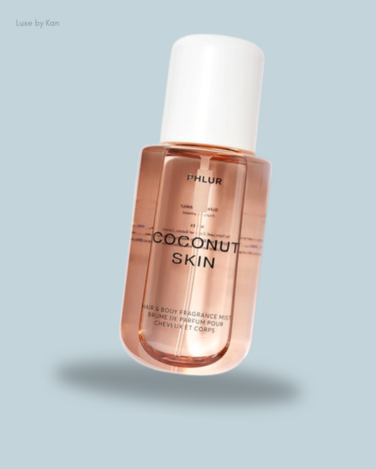 A bottle of PHLUR's Coconut Skin hair and body fragrance mist, featuring a minimalist design and a pale pink liquid.