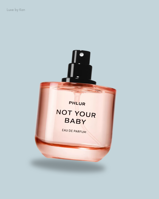A bottle of Phlur "Not Your Baby" Eau de Parfum in a minimalist design, featuring a black spray nozzle.