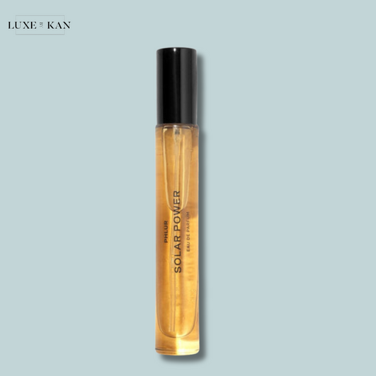 A sleek glass bottle of Phlur Solar Power perfume, featuring a black cap and a golden liquid.
