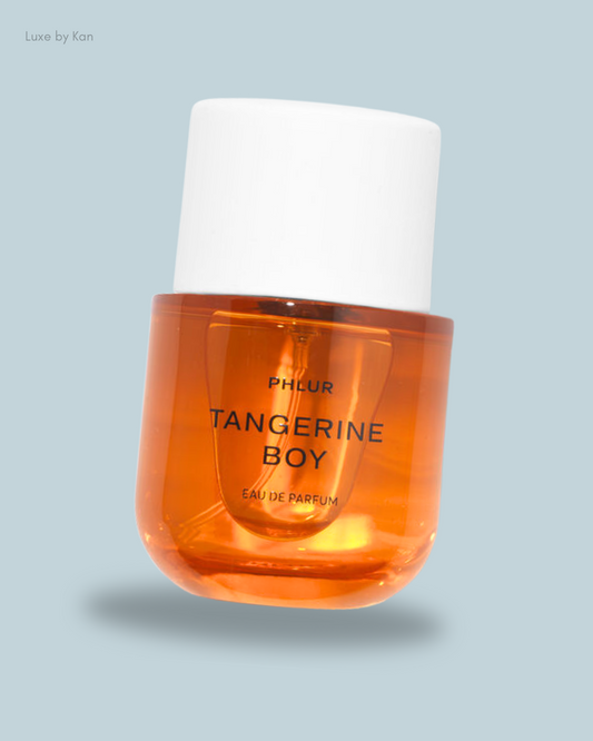 A stylish orange perfume bottle labeled "Tangerine Boy" by Phlur, featuring a sleek white cap.