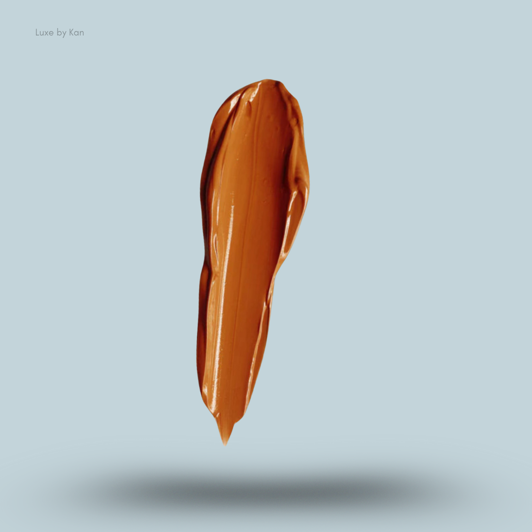 A single brushstroke of Plouise's orange-toned makeup base with light reflecting off its smooth surface against a pale blue background.