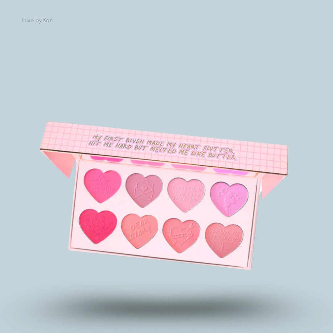 Plouise "My First Blush" palette, containing eight heart-shaped pans of blush in varying shades of pink, displayed in an open light pink container.