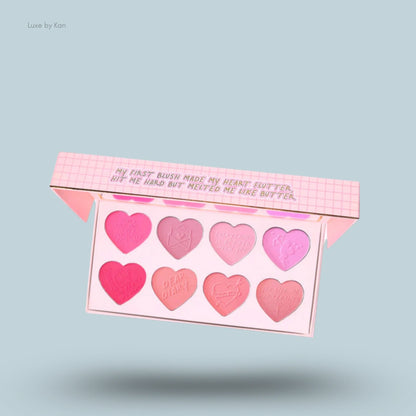 Plouise "My First Blush" palette, containing eight heart-shaped pans of blush in varying shades of pink, displayed in an open light pink container.