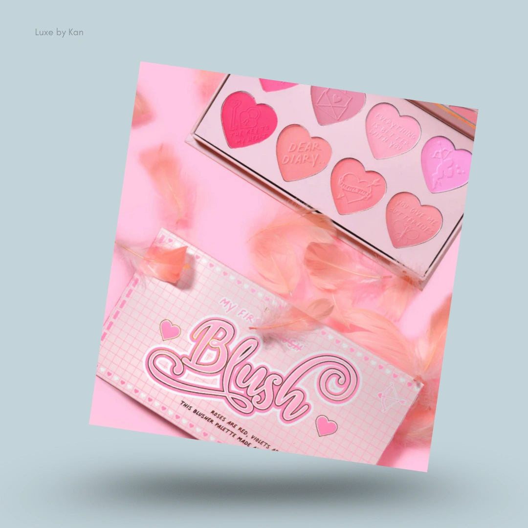 Plouise "My First Blush" palette displaying heart-shaped blush shades, with pink feather props.